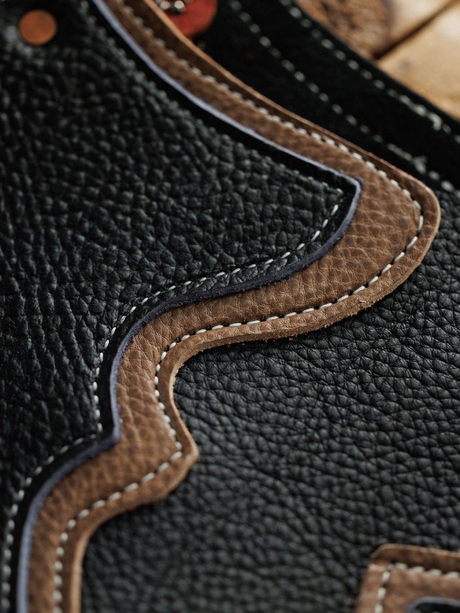 Close-up of black and brown textured leather with decorative stitching and wavy edges, highlighting the craftsmanship of Sheridan Chinks {Youth} by Savannah Sevens western life{&}style.