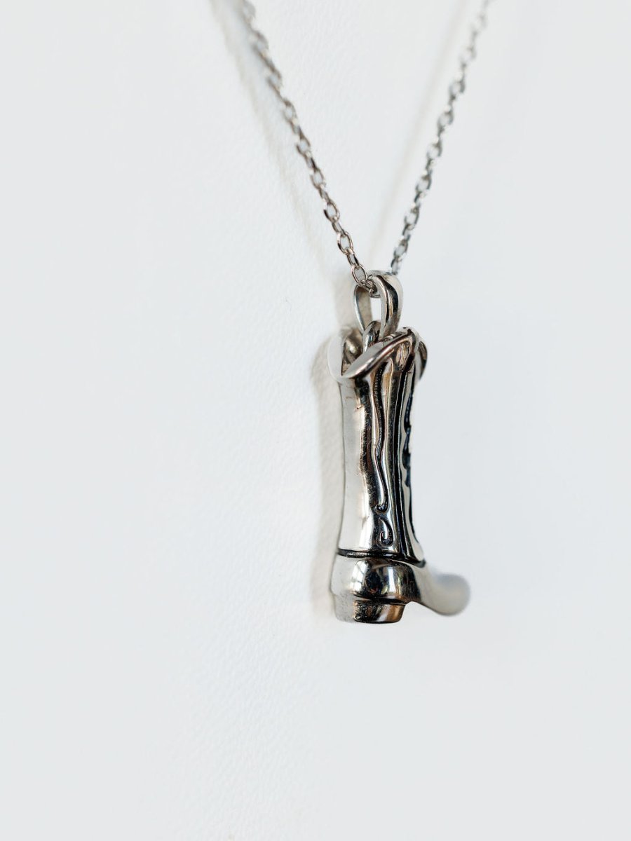 The Silver Cowgirl Boot Necklace by Savannah Sevens western life{&}style features a detailed boot pendant, bringing western charm against a plain white background.