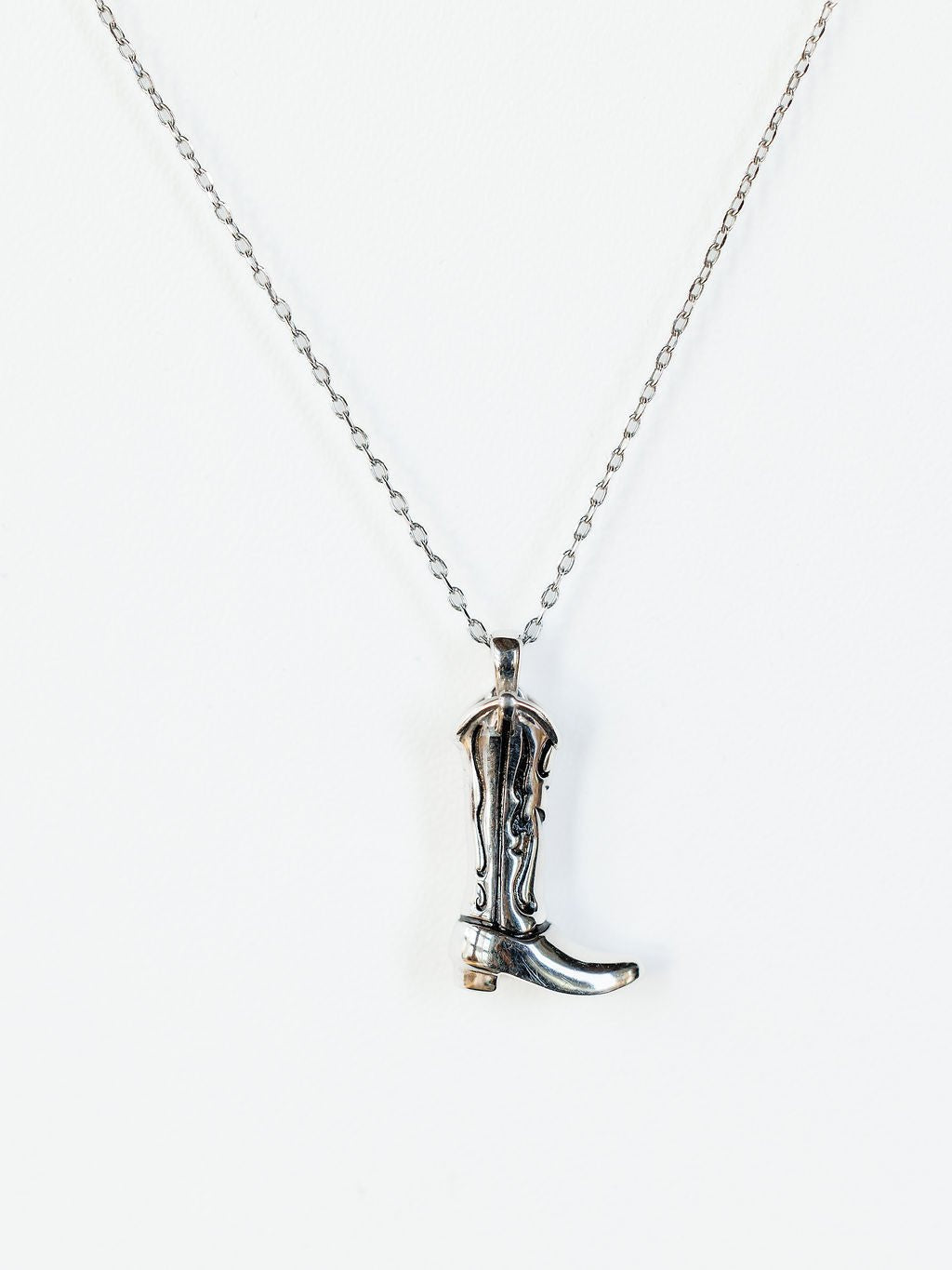 The Silver Cowgirl Boot Necklace by Savannah Sevens western life{&}style features a detailed pendant, beautifully displayed against a white background.