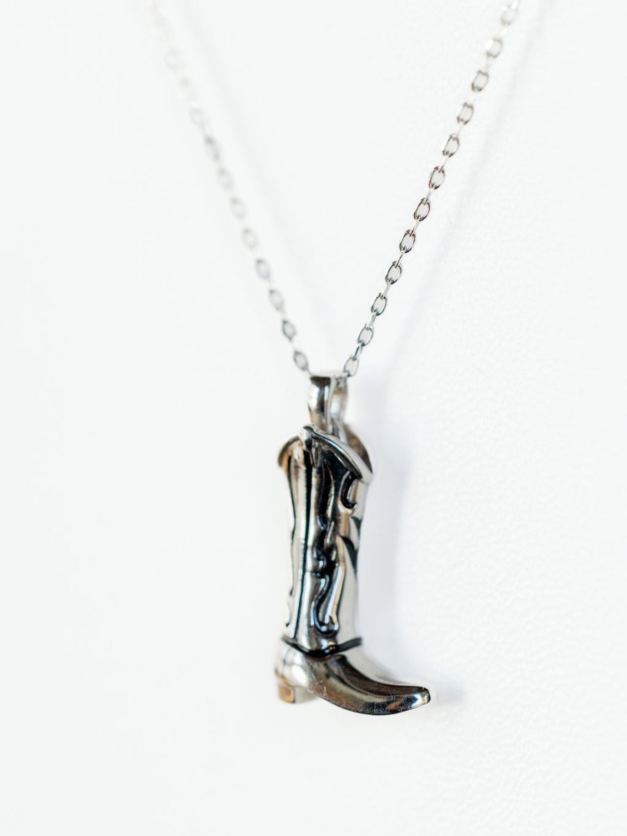 The Silver Cowgirl Boot Necklace by Savannah Sevens western life{&}style features a silver boot pendant on a delicate chain, shown against a white background.