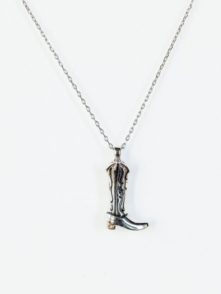 The Silver Cowgirl Boot Necklace by Savannah Sevens western life{&}style features a detailed pendant, beautifully displayed against a white background.