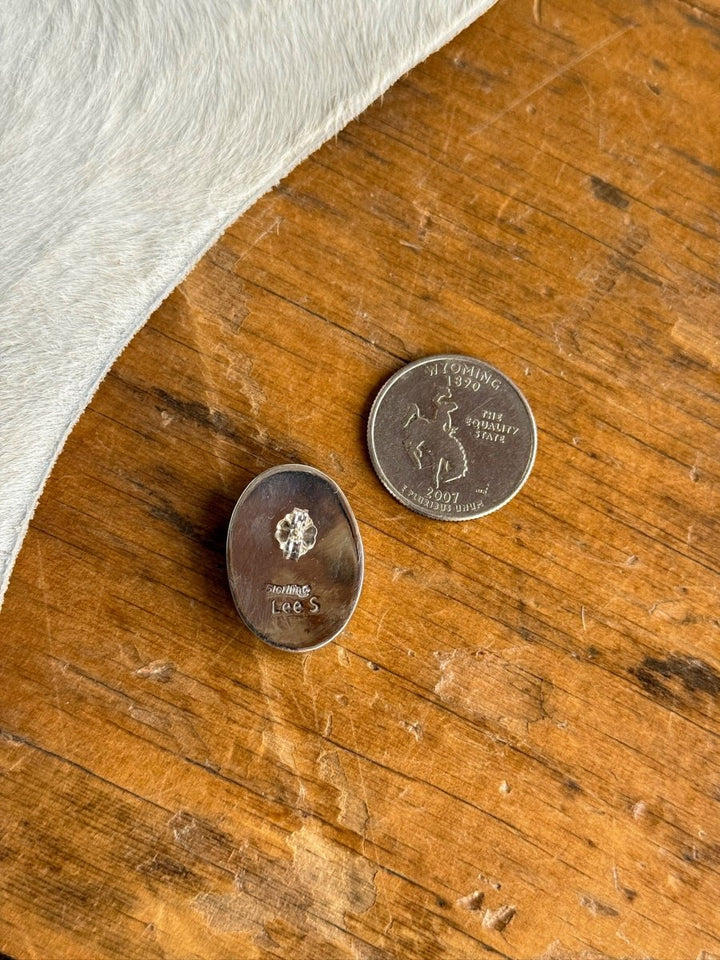 A pair of Slidell Earrings by Savannah Sevens western life{&}style rests beside a Wyoming state quarter on a wooden surface, with white animal hide visible in the corner.