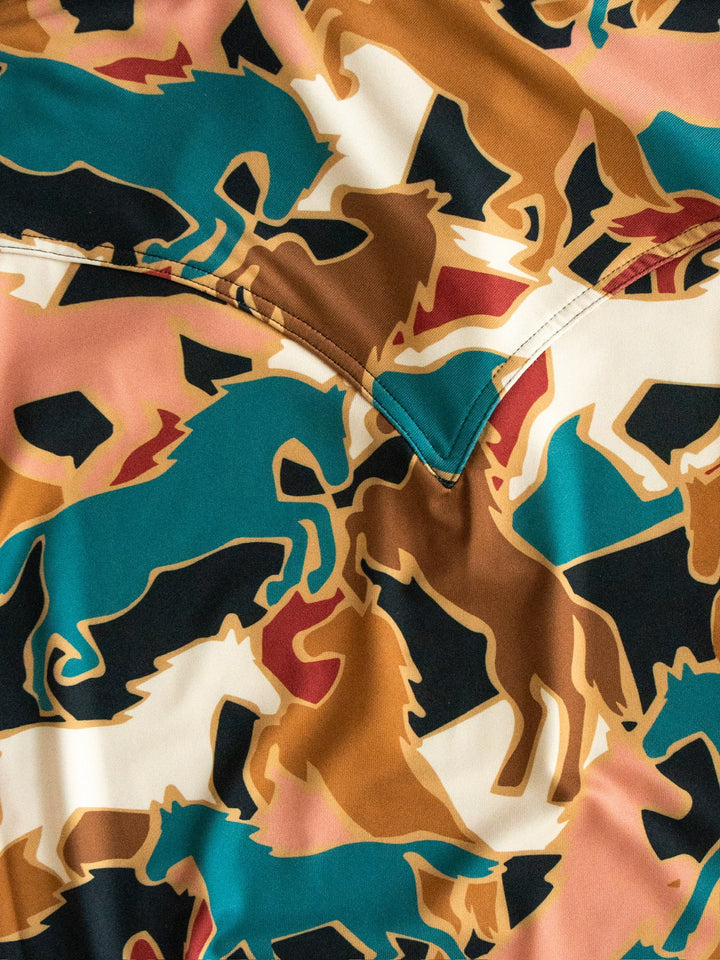 The Socorro Western Graphic Top by Savannah Sevens western life{&}style showcases a patterned fabric with overlapping horse silhouettes in teal, brown, black, and tan, highlighted by distinctive V-shaped stitching at the center—making it the ideal choice for anyone seeking a unique horse print shirt or chic western graphic top.