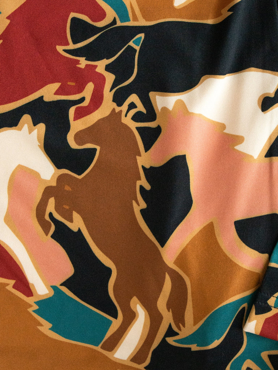 The Socorro Western Graphic Top by Savannah Sevens western life{&}style showcases an abstract pattern of overlapping horse silhouettes in brown, black, white, and tan on a vibrant multicolored fabric background—perfect for anyone seeking a unique horse print or standout western graphic top.