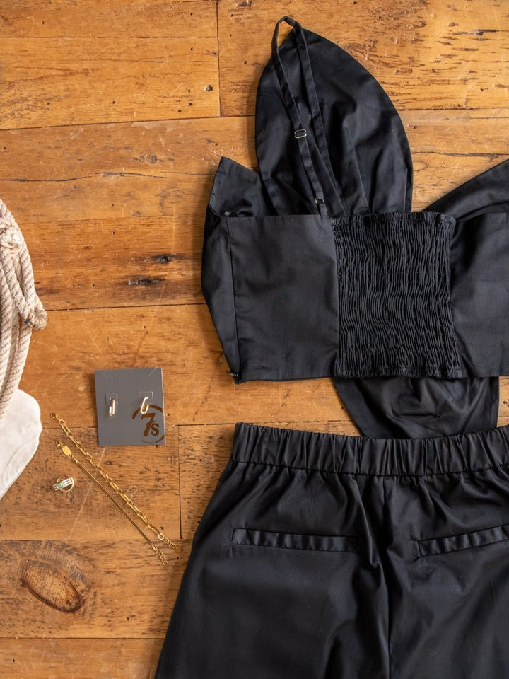 The Solvay {Set} by Savannah Sevens western life{&}style features a black crop top with smocked details and matching high-waisted pants, styled with gold jewelry and a bag for a chic look.