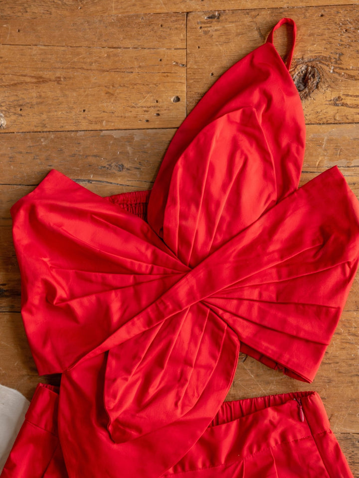 The Solvay {Set} by Savannah Sevens western life{&}style features a vibrant red, one-shoulder crop top with a large bow design—perfectly paired with high waisted pants for a chic, modern look.