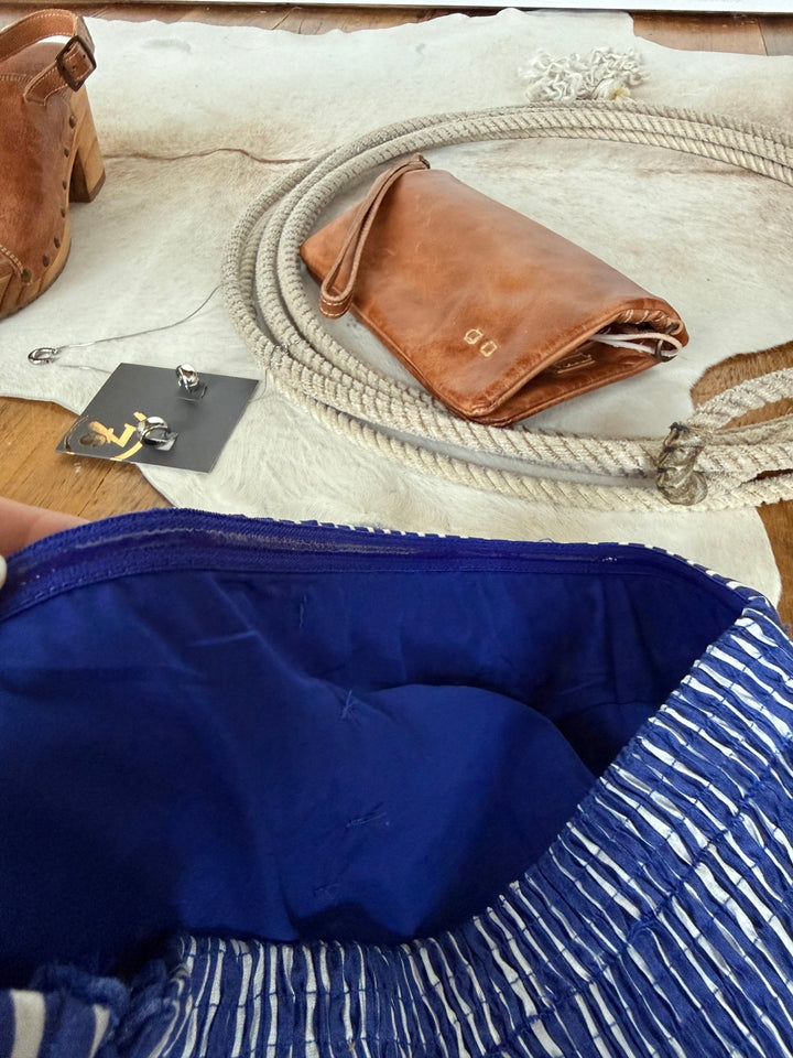 The Southport Striped Strapless Dress by Savannah Sevens western life{&}style. Behind it sit a tan leather purse, rope, brown shoe, and silver earrings on a card, all arranged atop a light-colored surface.