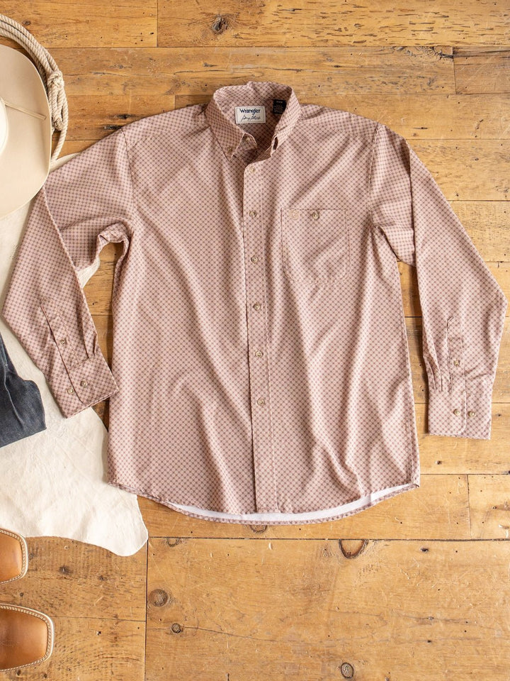 A light brown Strait Wrangler Men's Performance Button Up from Savannah Sevens western life{&}style, featuring a small geometric pattern, is laid flat on a wooden floor. A hat and jeans are partially visible next to the shirt.