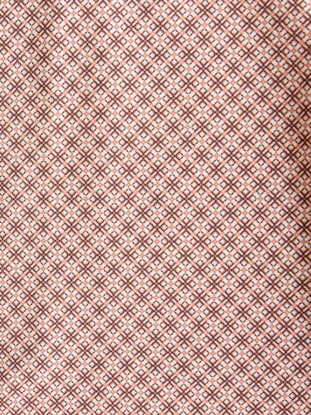A close-up of the fabric from the Strait Wrangler Men's Performance Button Up by Savannah Sevens western life{&}style, featuring a repeating diamond and dot pattern in brown and pink tones that creates a geometric, symmetrical design.