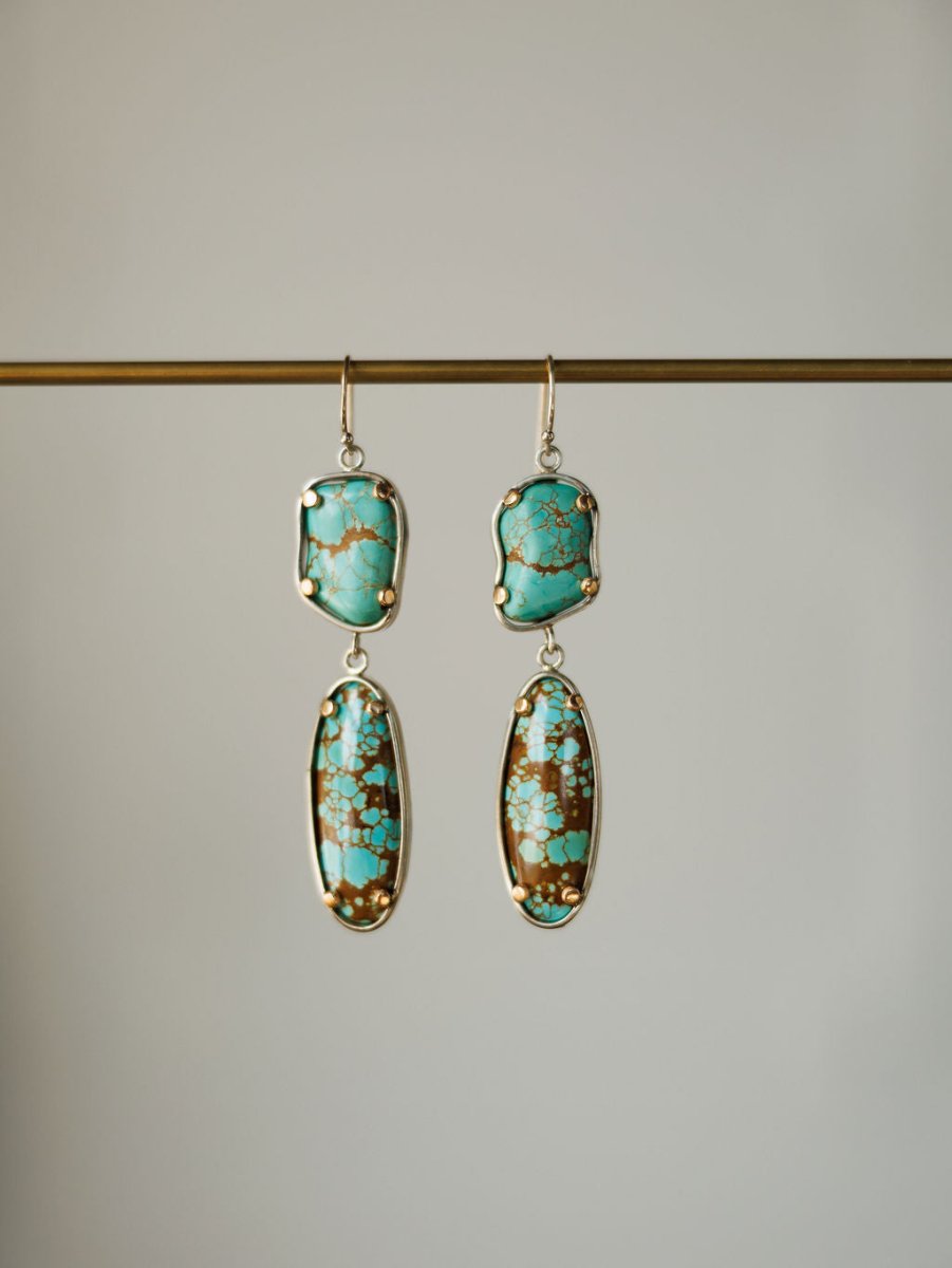 The Taos Earrings by Savannah Sevens western life{&}style feature Number 8 turquoise stones on top and elongated turquoise and brown oval drops set in gold, hanging from a horizontal rod.