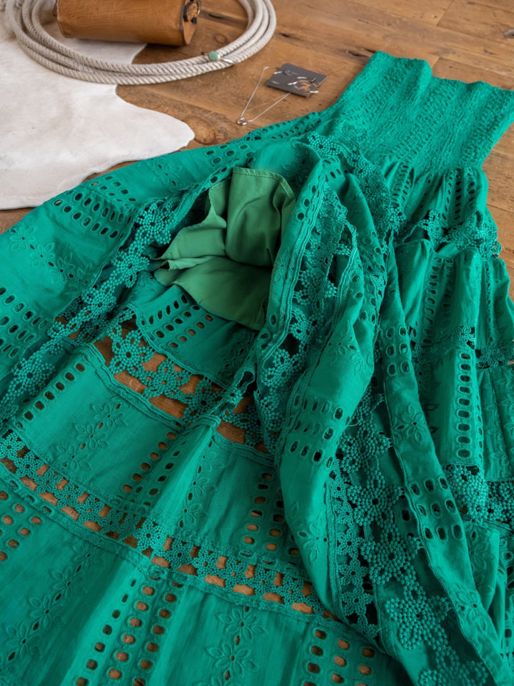 The Tekoa Jade Teal Crochet Strapless Dress by Savannah Sevens western life{&}style is displayed on a wooden floor with a white rug and necklace in the background.