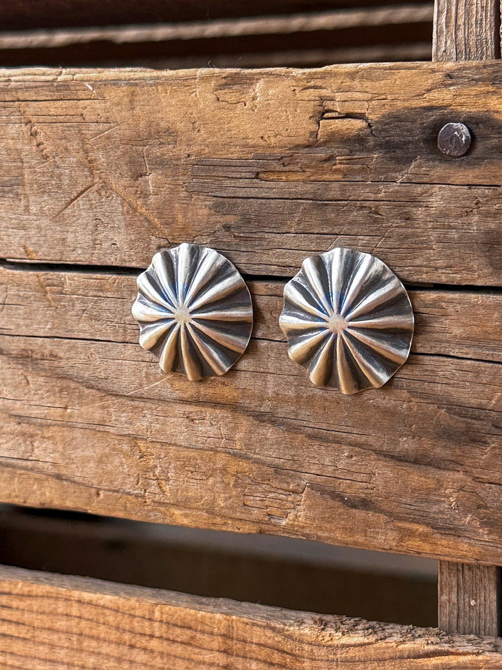 Two Tempe Sterling Silver Parachute Earrings by Savannah Sevens western life{&}style are displayed on rustic, weathered wooden planks, highlighting their shiny, textured surface and raised, radiating scalloped pattern.