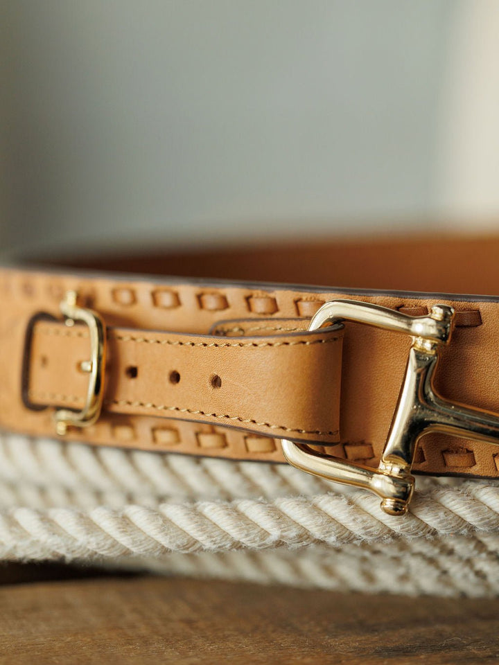 Close-up of the Texarkana Belt by Savannah Sevens western life{&}style, featuring light brown leather with decorative stitching and a shiny gold buckle, displayed on a coiled white rope.