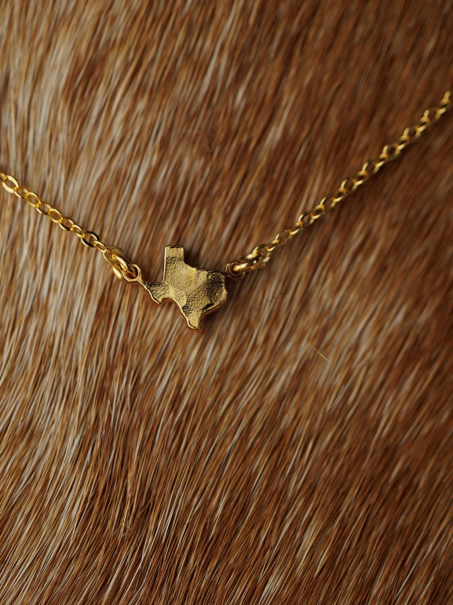 The Savannah Sevens western life{&}style Texas Necklace, featuring a state-shaped pendant, is displayed on a brown and white fur background.