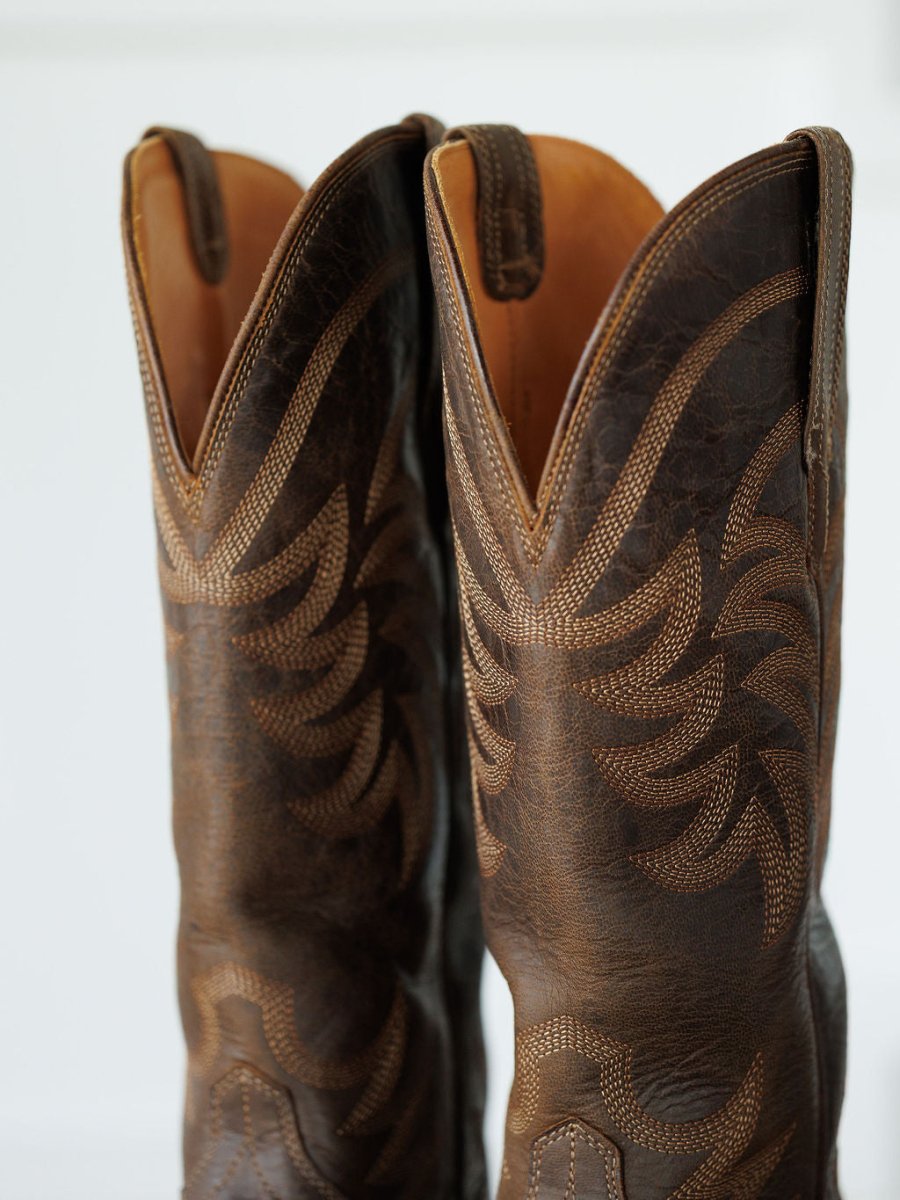 A close-up of The Annie Boot {Cafe} by Savannah Sevens western life{&}style shows two premium goat leather snip toe boots with intricate light stitching on the shafts and pull tabs at the top. Boots handmade by Tecovas.
