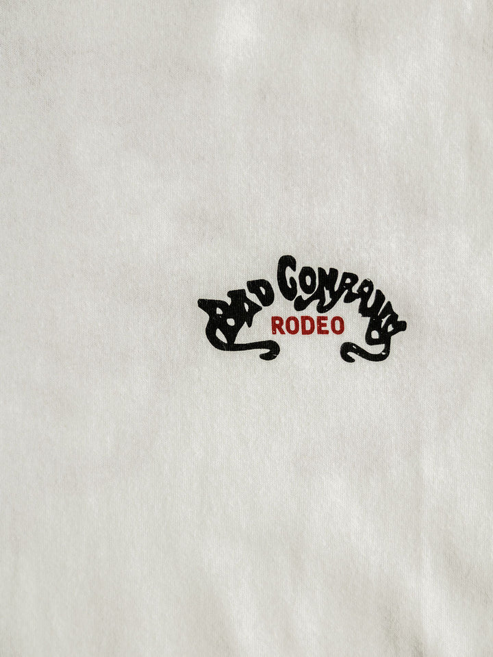 The Bad Company Men's Graphic Tee by Savannah Sevens western life{&}style is a white men's shirt with bold black "BAD COMPANY" above red "RODEO," blending classic style with the Bad Company Rodeo vibe.