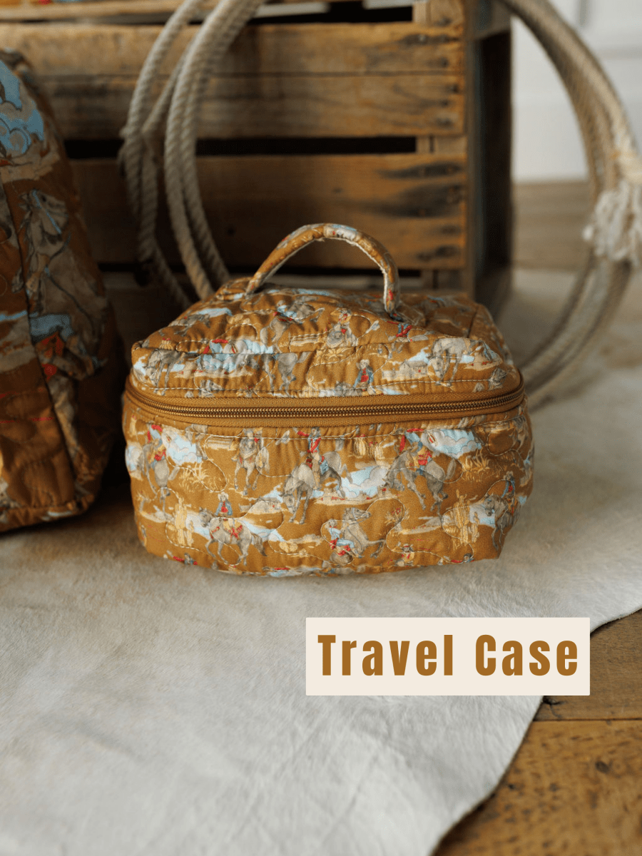 A patterned brown quilted bag set from The Big Sky Collection by Savannah Sevens western life&style rests on a beige rug before a wooden crate, with "Travel Case" in bold at the bottom right.