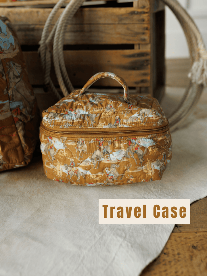 A patterned brown quilted bag set from The Big Sky Collection by Savannah Sevens western life&style rests on a beige rug before a wooden crate, with "Travel Case" in bold at the bottom right.