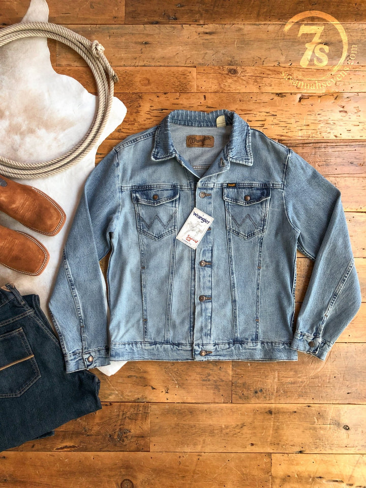 The Boden {Men's} jacket from Savannah Sevens western life{&}style is displayed on a wooden floor with jeans, brown boots, a rope, and a white cowhide rug. The 7s company logo is shown in the top right corner.