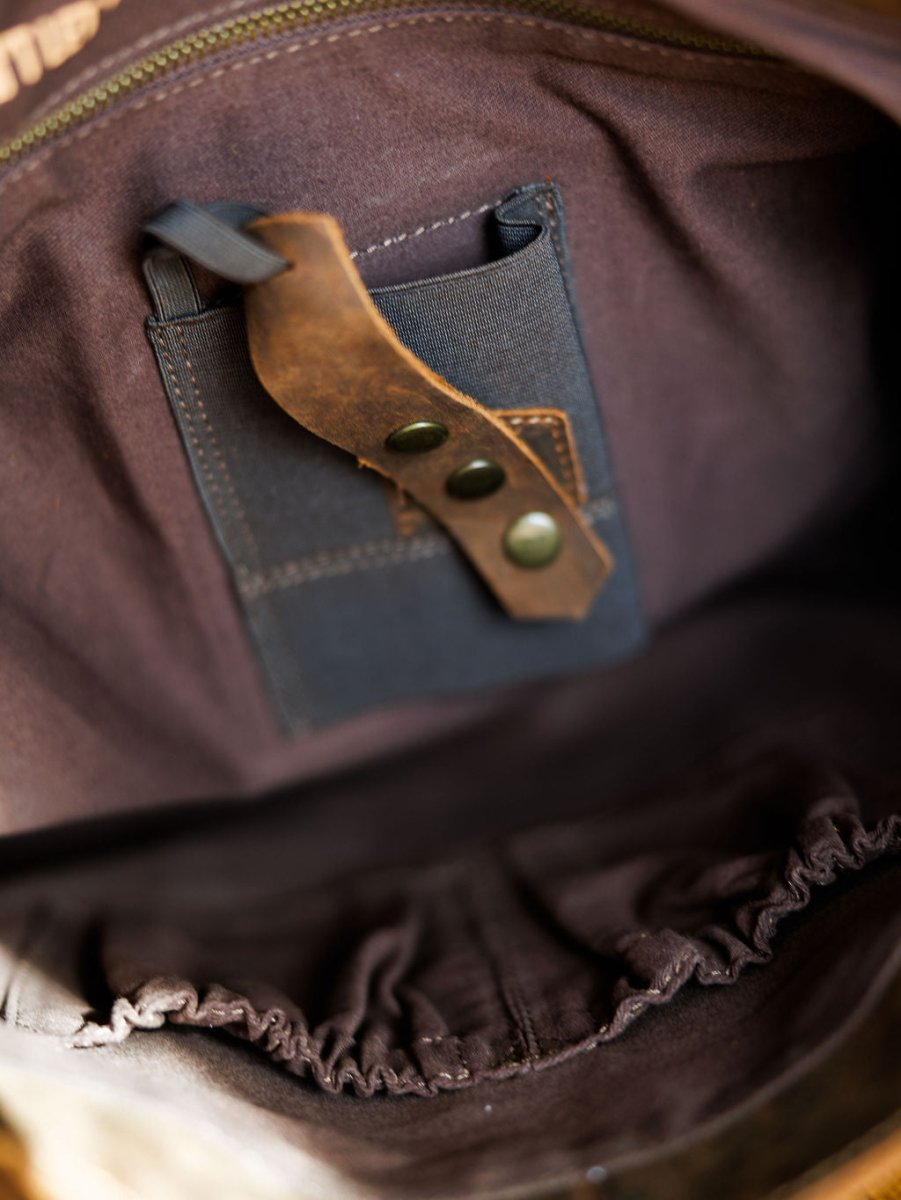 Close-up of The Broken Arrow handbag by Savannah Sevens western life{&}style, showing the inner lining, zipper, small fabric pocket with leather strap, metal studs, and an elastic pouch for organizing your essentials.