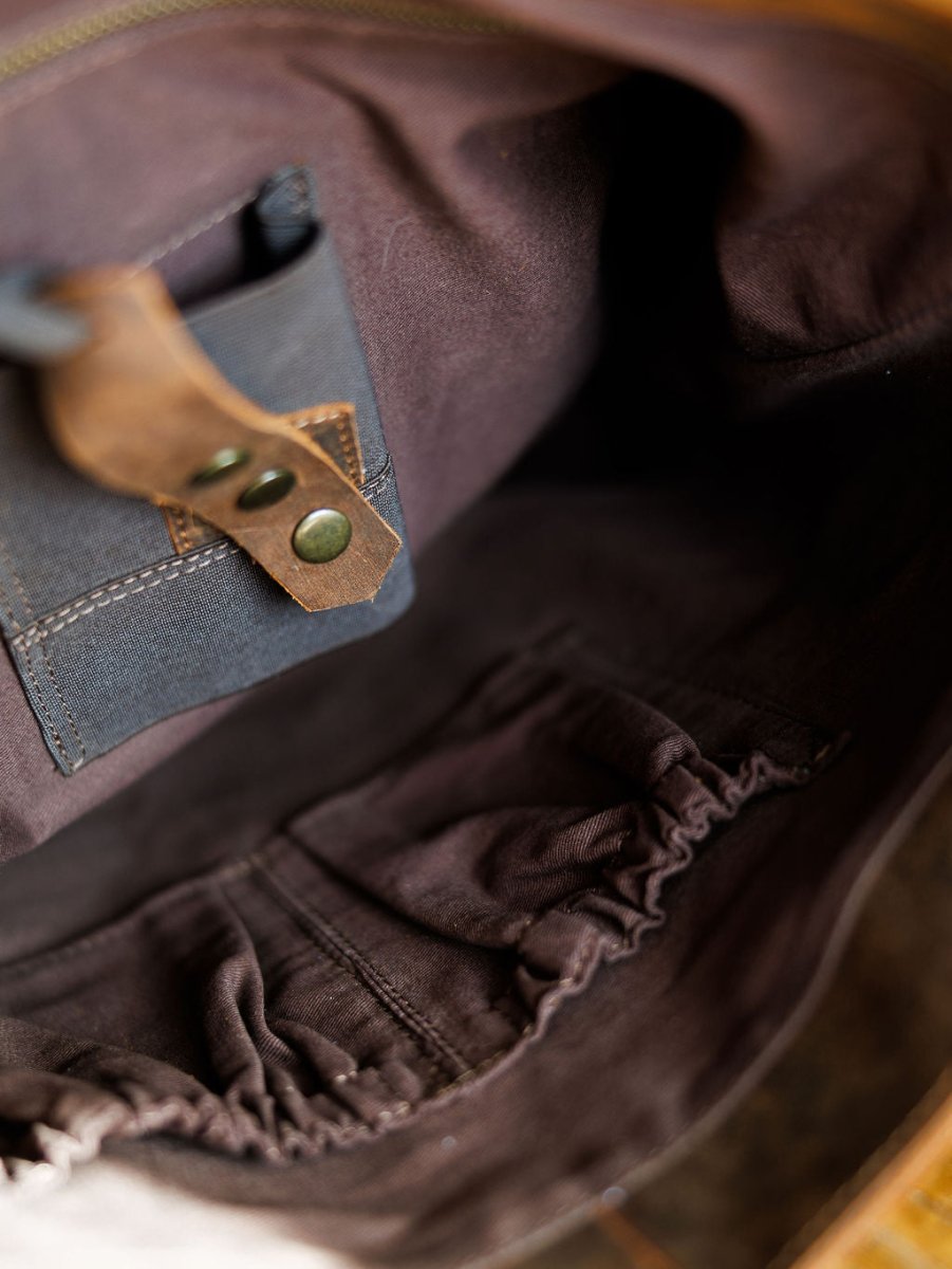 Interior of The Broken Arrow by Savannah Sevens western life{&}style, showing a small pocket with a leather strap and metal rivets, plus elastic gathered pockets—ideal for organizing items in this genuine leather handbag.