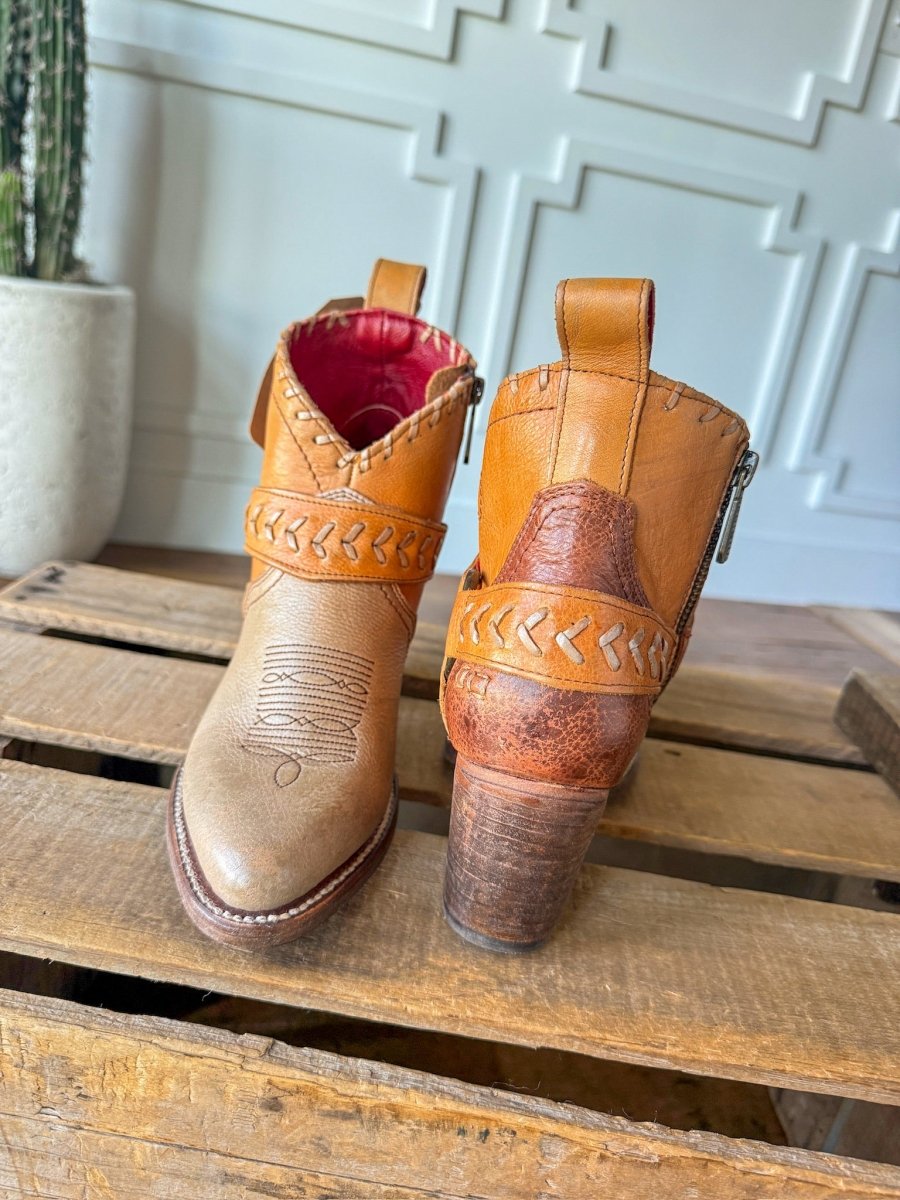 The Cadillacs by Savannah Sevens western life{&}style: tan leather western boots with decorative stitching and braided details, shown front and back on a wooden surface next to a cactus and a white paneled wall.