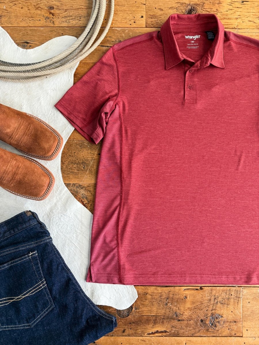 The Carlyle men's polo from Savannah Sevens western life{&}style, brown suede shoes, a coiled rope, and dark blue jeans are arranged on a rustic wooden floor with a white cowhide rug.