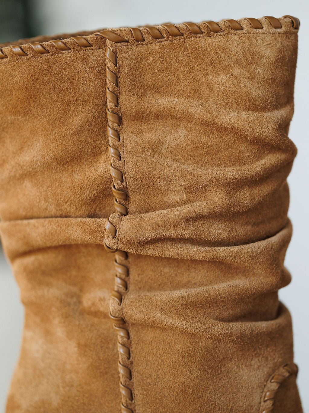 Close-up of The Cerritos by Savannah Sevens western life{&}style: a tan suede bootie with decorative stitching, stacked heel, and slouchy ruched seam. Suede texture and fine craftsmanship are clearly shown.