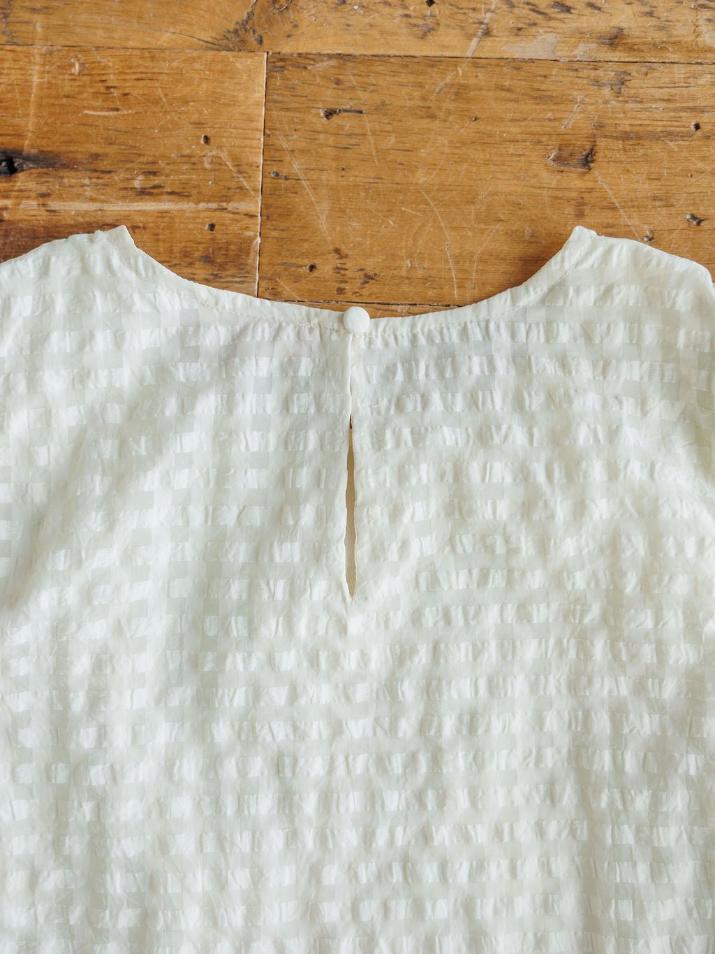 A close-up of the back neckline of The Elrosa {Set} blouse by Savannah Sevens western life{&}style, featuring textured white fabric, a small slit, and a single button—ideal for pairing with shorts or as part of this floral embroidered set.