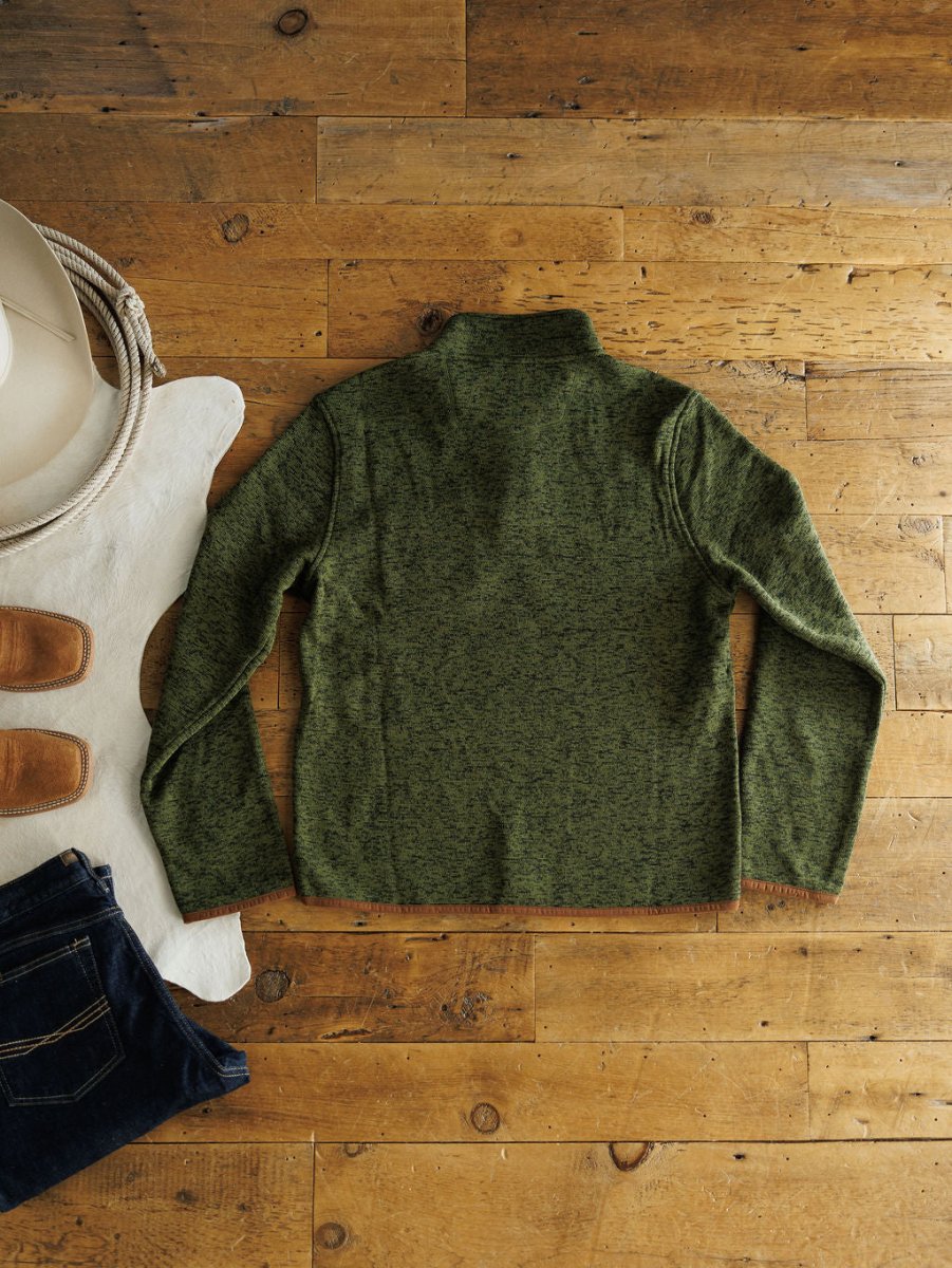 The Kempton {Men's} pullover by Savannah Sevens western life{&}style is displayed flat on wood with jeans, boots, a white cowboy hat, rope, and a cowhide rug for a rugged western look.