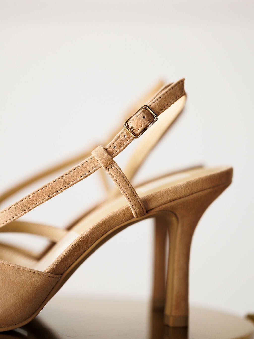 Close-up of "The Lafayette" by Savannah Sevens western life{&}style—beige suede stiletto heel sandal with an adjustable buckle slingback strap, highlighting the detailed strap and heel against a neutral background.