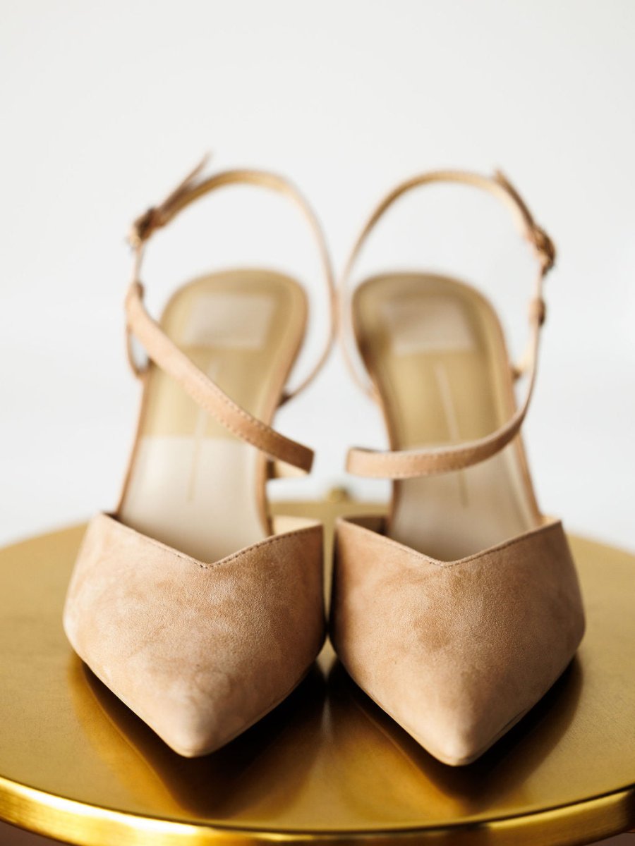 The Lafayette by Savannah Sevens western life{&}style: beige suede stiletto heels with pointed toes and adjustable buckles, shown on a round gold surface against a white background.