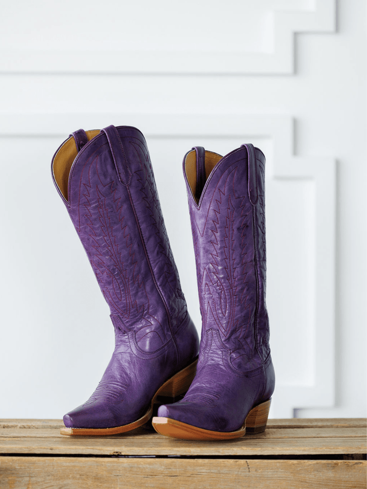 The Maricopa by Savannah Sevens western life{&}style: tall plum leather snip toe western boots with decorative stitching, shown side by side on a wooden surface against a white geometric-patterned background. Made by Black Star. 
