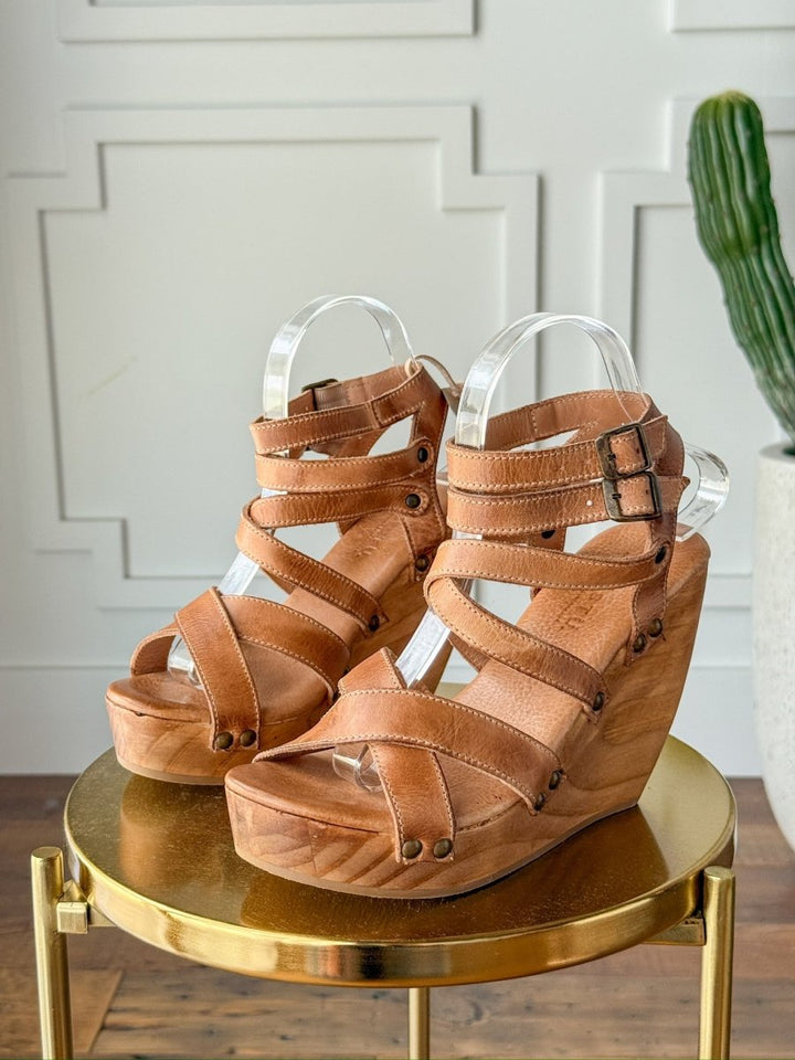 The Mesilla by Savannah Sevens western life{&}style: Tan leather open toe heels with multiple straps and buckles, wooden platform heels, showcased on a round gold table in a stylish room with a cactus in the background. Made by BedStu. 
