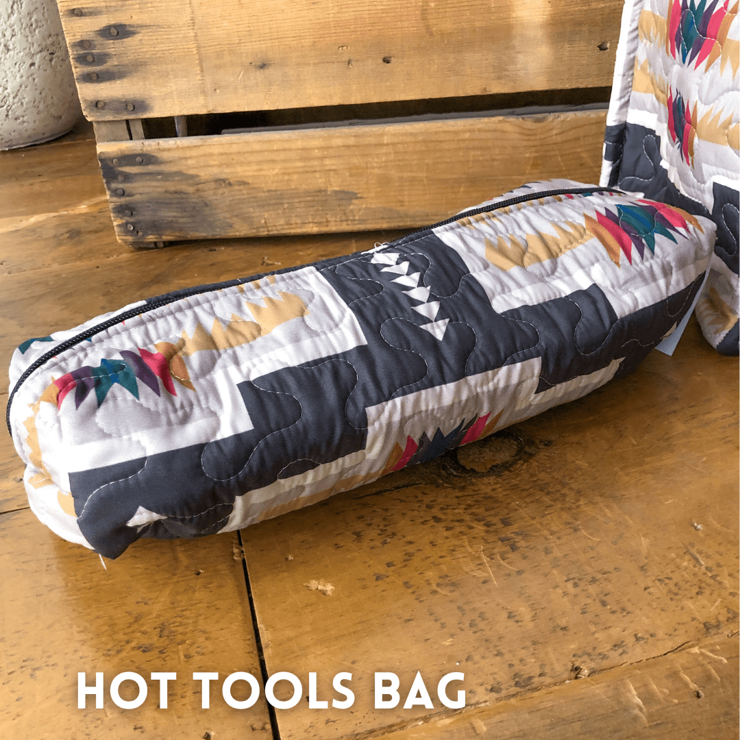 A quilted, southwest-patterned bag with a zipper from The Muskogee {Collection} by Savannah Sevens western life{&}style sits on wood, beside a matching item. By Ida Mae. 