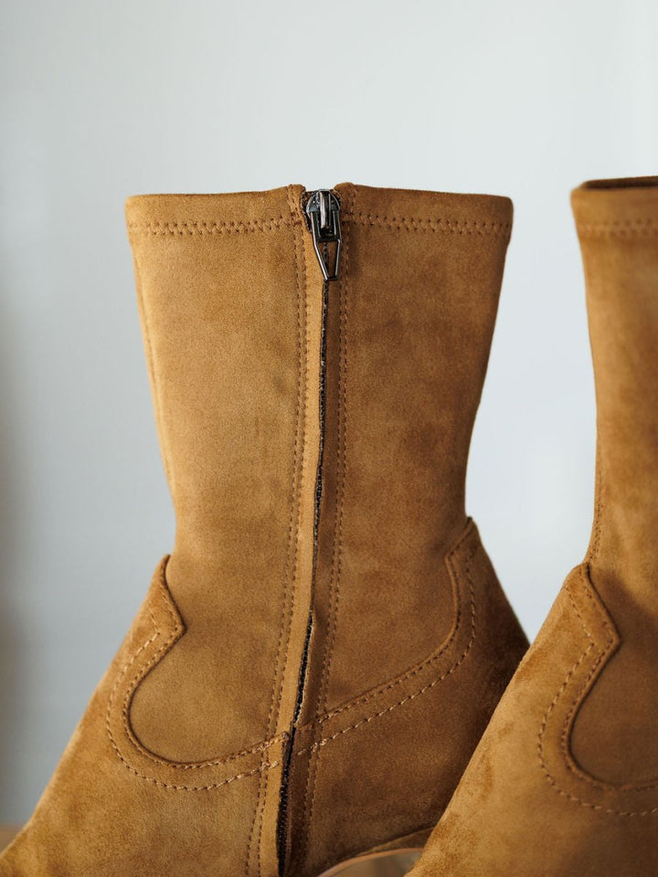 Close-up side view of The Palmetto faux suede bootie by Savannah Sevens western life{&}style, featuring visible stitching and a zipper against a light, neutral background.