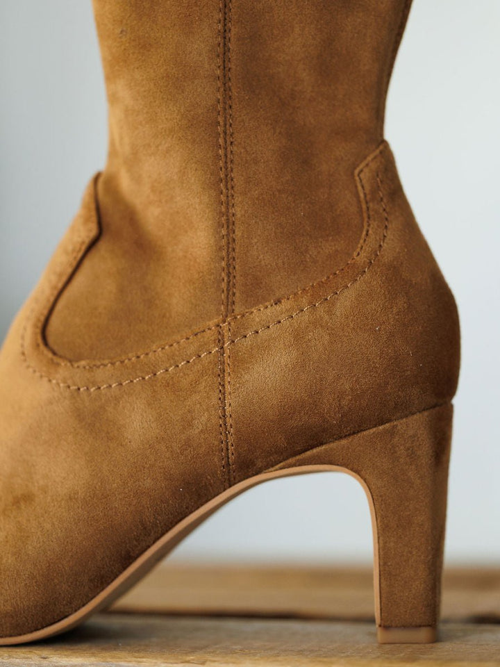 Close-up of The Palmetto bootie by Savannah Sevens western life{&}style, featuring tan faux suede, detailed stitching, and a curved upper and heel design against a neutral background.