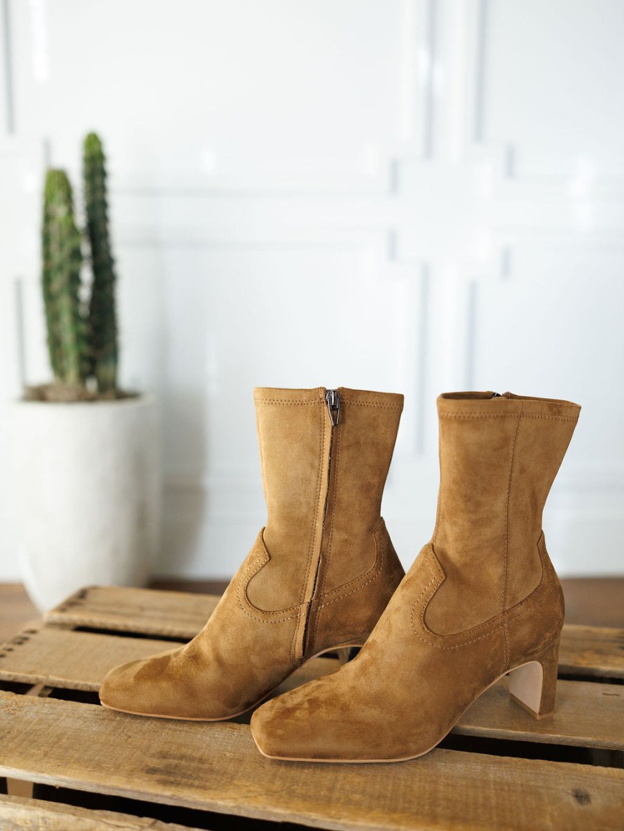 The Palmetto by Savannah Sevens western life{&}style: tan faux suede western booties with low heels and side zippers, displayed on wood with a potted cactus in the background.