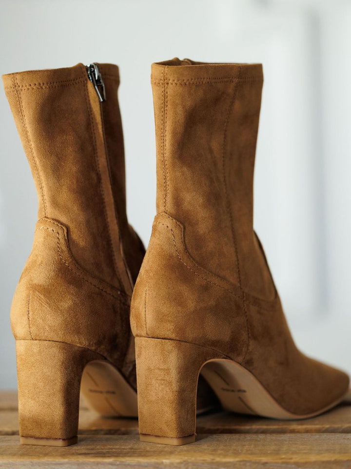 The Palmetto booties by Savannah Sevens western life{&}style feature tan faux suede, side zippers, and a chic square toe, shown on a wooden surface with a neutral backdrop.