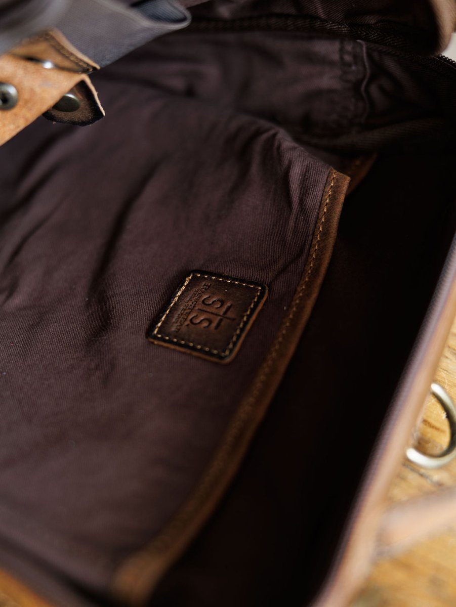 Close-up of The Ranch Hand by Savannah Sevens western life{&}style, showing the genuine leather interior with a stitched patch embossed with 315, lining details, and part of a metal clasp. By STS> 
