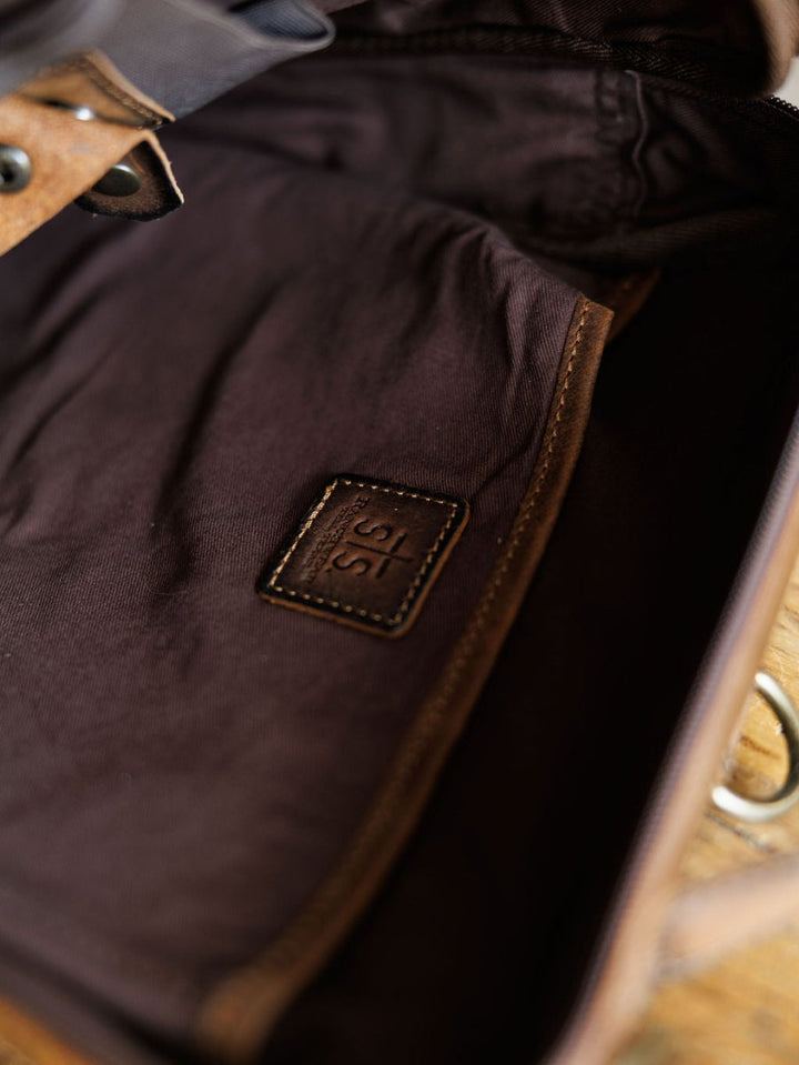 Close-up of The Ranch Hand by Savannah Sevens western life{&}style, showing the genuine leather interior with a stitched patch embossed with 315, lining details, and part of a metal clasp. By STS> 