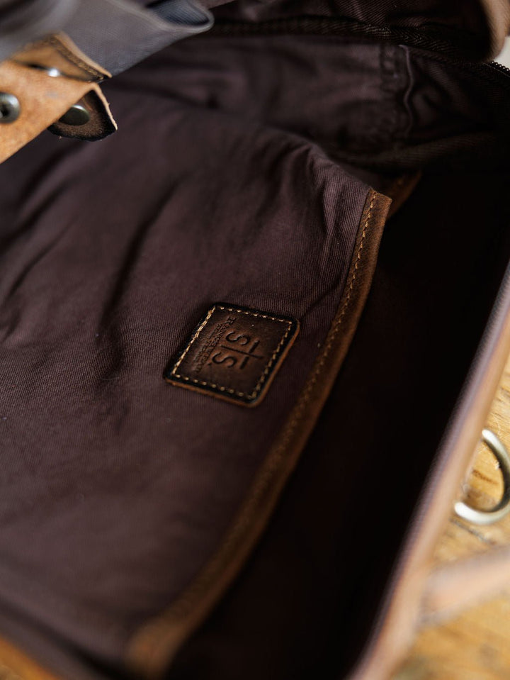 Close-up of The Ranch Hand by Savannah Sevens western life{&}style, showing the genuine leather interior with a stitched patch embossed with 315, lining details, and part of a metal clasp. By STS> 