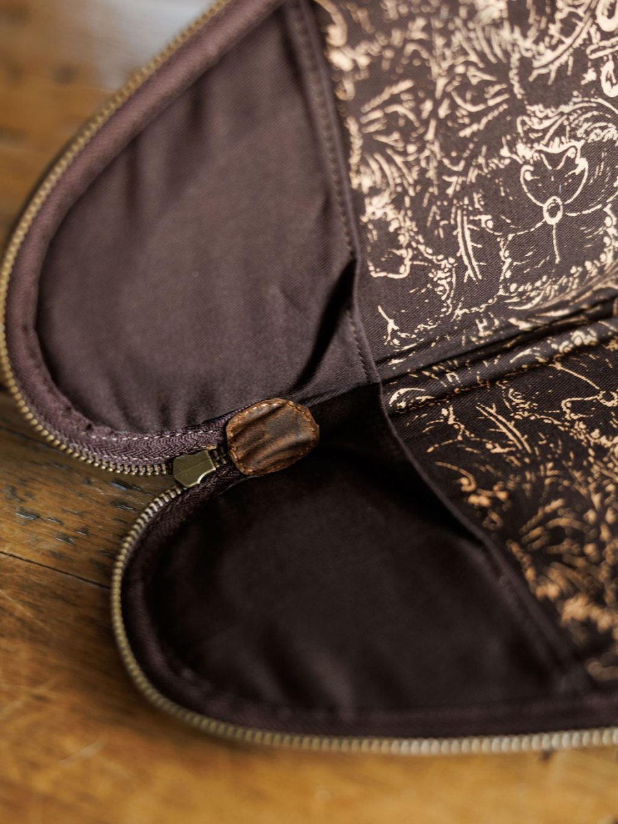 A close-up of The San Antonio leather pistol case by Savannah Sevens western life{&}style, featuring a floral-patterned interior and partially open on a wooden surface. By STS. 