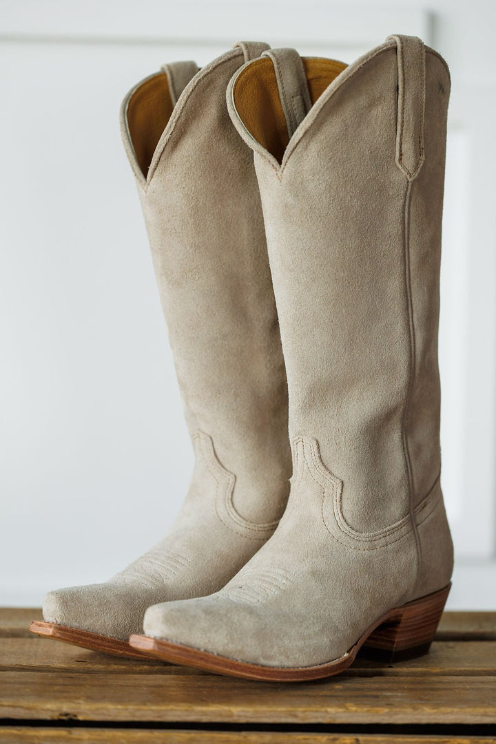 The Shiloh by Savannah Sevens western life{&}style: a pair of light beige suede western boots with snip toes and wooden heels, standing upright on a wooden surface against a white background. Made by Black Star. 