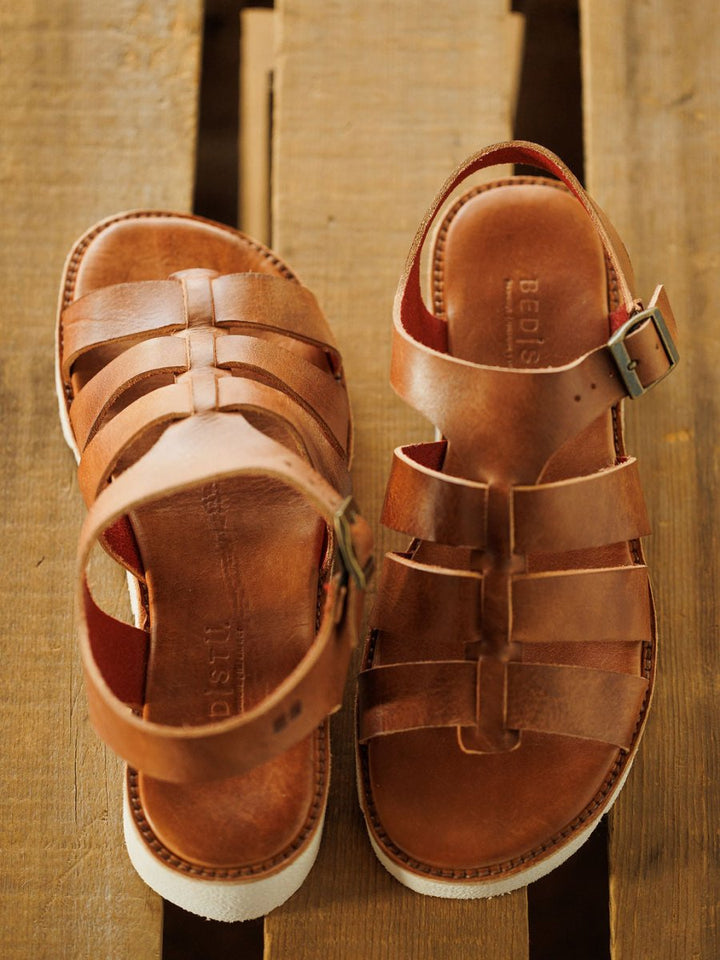 A pair of Savannah Sevens western life{&}style The Tuscola brown leather platform sandals with cushioned insoles, white soles, and buckled ankle straps, displayed on a wooden pallet.