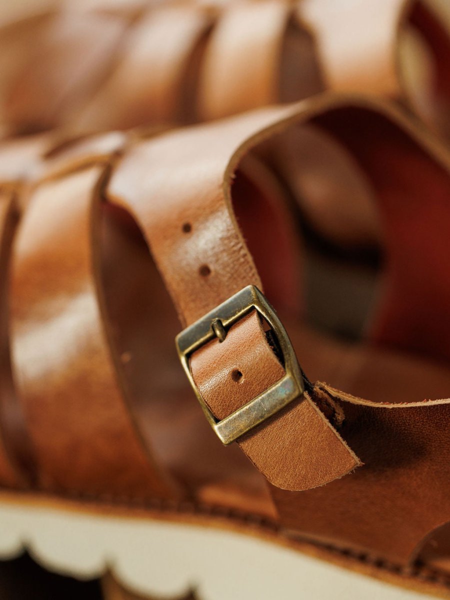 Close-up of The Tuscola by Savannah Sevens western life{&}style: leather platform sandal with a brass buckle, textured leather straps, precise stitching, white scalloped sole, and cushioned insole for comfort.