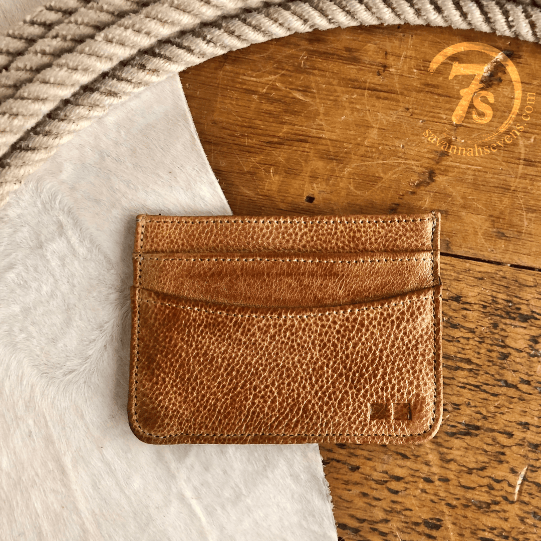 The Tilden Wallet by Savannah Sevens western life{&}style sits on a wooden surface beside a coiled rope and white textured fabric. The Savannah Sevens logo appears in the upper right corner.