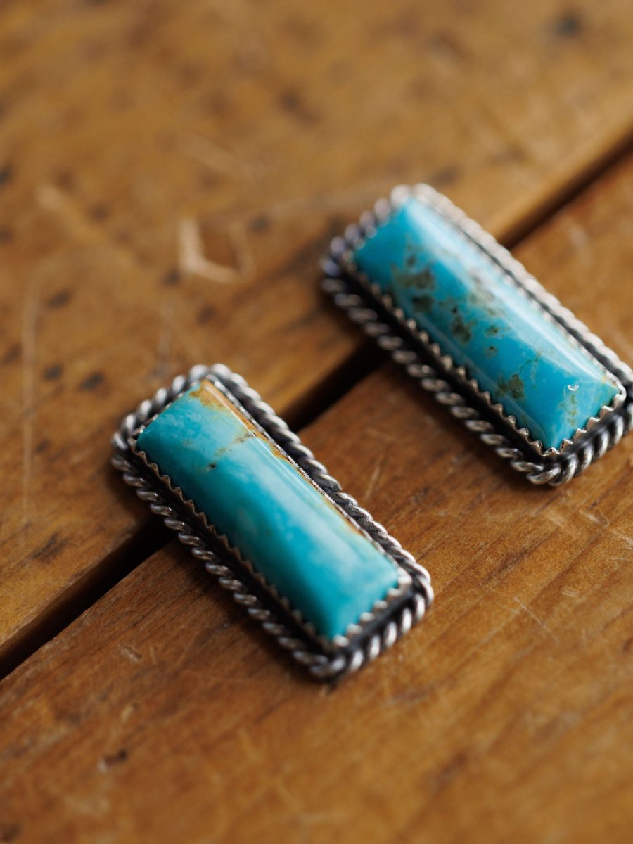 The Toano Earrings by Savannah Sevens western life{&}style feature two rectangular turquoise stones in sterling silver rope-edged frames, each pair showcasing unique natural patterns and Navajo handcrafted artistry.