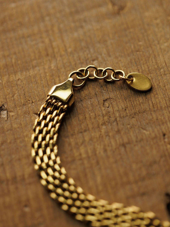 The Vienna Bracelet by Savannah Sevens western life{&}style is a hypoallergenic 18K gold filled chain with a clasp and extension links, shown in a close-up on a textured wooden surface.