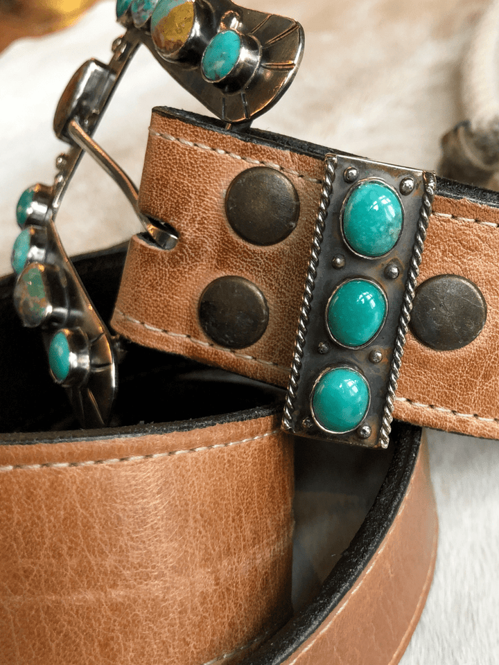 Close-up of Savannah Sevens western life{&}style's Wallowa Belt Keeper with German silver and turquoise stone accents, paired with sunglasses featuring turquoise details on the arms. Background is out of focus.
